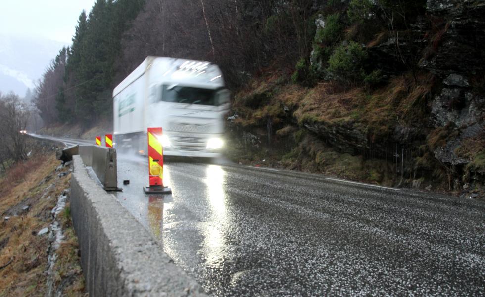 En lastebil som kjører langs en regnvåt vei på E134.