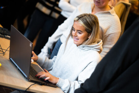 jente som smiler foran laptop