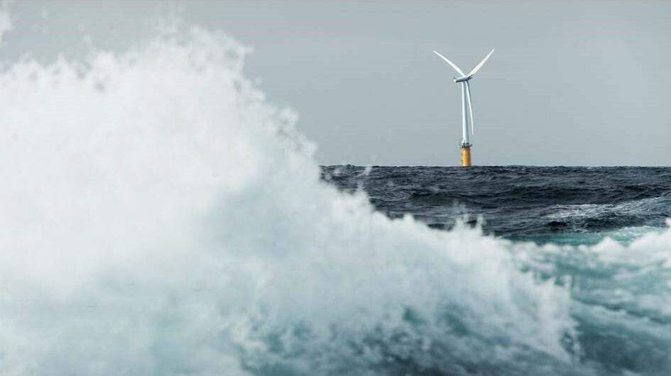 Bølger som slår med en vindturbin på havet i bakgrunnen.