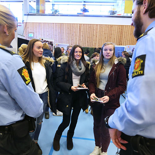 Tre unge jenter snakker med to politibetjenter på Yrkesmessen