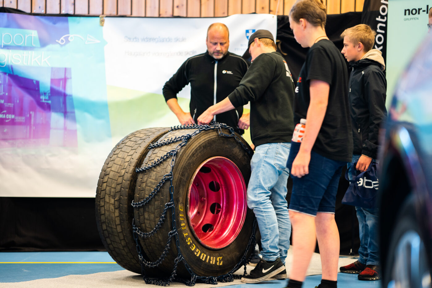 Noen unge gutter ser på et stort dekk på ei yrkesmesse.